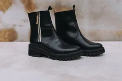 Botas de cuero marrón con suela track de goma negra, cierre lateral en color rojo y detalle de tira trasera al tono.