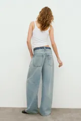 Jeans de tiro medio con cinco bolsillos, cintura doble a contraste y detalles de rotos. Cierre frontal con cremallera y botones metálicos.
