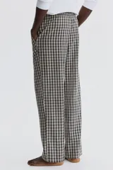 Pantalón de corte relajado confeccionado en popelina de algodón con estampado de cuadros. Presenta cintura elástica con cordón de ajuste y bolsillos laterales.