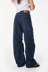 Pantalón jean de corte amplio y relajado, color azul oscuro, con bolsillos traseros grandes y detalles de costuras marcadas.