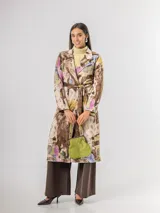 Trench de diseño urbano con acabado agamuzado, de corte recto y largo midi. Presenta un estampado abstracto multicolor con tonos rojizos, azules y ocres, cuello solapa, mangas largas y cinturón ajustable en la cintura.