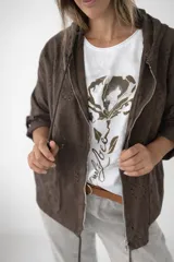 Campera fina de algodón color gris topo con capucha y cierre frontal. Presenta detalles tipo broderie, corte holgado y mangas con opción de remangar.