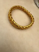 Pulsera de resina flexible con diseño trenzado y acabado brillante, con relleno de lámina metálica en tonos dorados, plateados y cobrizos.