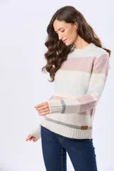 Buzo de tejido de punto con diseño de rayas horizontales en tonos neutros, beige y detalles en rosa y gris. Presenta cuello redondo, mangas largas y terminaciones en rib acanalado en puños y ruedo. Incluye una pequeña etiqueta de cuero sintético en el lateral inferior.