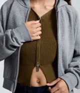 Cardigan de punto color verde militar, con cuello en V, mangas largas abullonadas y cierre frontal de cremallera bilateral.