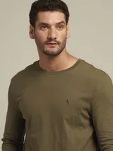 Remera de manga larga color verde militar, con cuello redondo y logo bordado de un pájaro en el pecho.