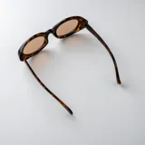 Lentes de sol con armazón ovalado de acetato traslúcido en tono gris oscuro y lentes oscuros.