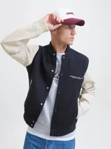 Campera bomber de manga larga y cuello estilo baseball, color azul marino con mangas beige. Tiene cierre de botones, puños acanalados y bolsillos delanteros. Confeccionada en tejido plano con detalle de logo.