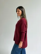 Sweater de punto color bordó, con escote en V, manga larga y costura central vertical decorativa.