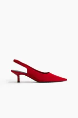 Zapatos destalonados de satén color rojo, con punta fina y taco bajo tipo kitten heel. Presentan una tira elástica en el talón para mayor ajuste.