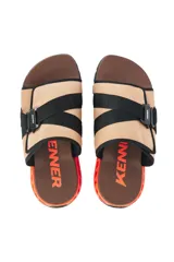 Chinelas Kenner modelo Rakka Slide Pro, con capellada de tela color beige y ajuste mediante hebilla técnica negra. Presenta una base ergonómica marrón con estructura lateral geométrica en color naranja y suela negra.
