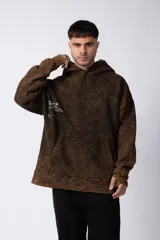 Buzo canguro con capucha, de calce oversize y efecto de lavado ácido en tono marrón. Presenta un bolsillo frontal tipo canguro y un pequeño estampado minimalista en el pecho.