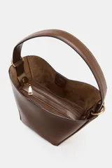 Bolso tipo saca de cuero marrón, con paneles laterales de gamuza en el mismo tono. Posee asa de hombro y correa bandolera extraíble. Incluye un bolsillo interior extraíble con cierre de cremallera.