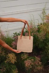 Bolso tipo tote de cuero color beige con textura tipo piel de cocodrilo. Tiene doble asa corta color marrón y un bolsillo externo. El interior contiene tres bolsillos y un llavero. Incluye correa larga extraíble.