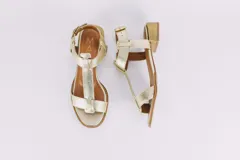 Sandalias de cuero doradas con tiras finas, suela plana y hebilla lateral.