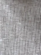 Camisa a rayas verticales grises y blancas, de lino, con cuello clásico, cierre frontal con botones, mangas abullonadas 3/4 con puños elásticos negros y corte holgado.