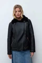 Chaqueta biker de cuero sintético negro con interior y solapas de piel sintética al tono. Presenta cierre frontal cruzado, mangas largas y textura granulada.