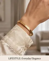 Esclava rígida de acero con baño de oro, caracterizada por un diseño geométrico grabado en toda su superficie.