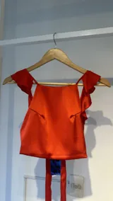 Top rojo de raso con breteles finos y volados en los hombros. Se ata en la espalda con lazos.