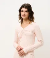 Blusa de pijama de manga larga confeccionada en viscolycra, con escote en V y detalle de frunce central con lazo. Presenta un estampado sutil de perritos sobre una base de color rosado.