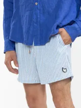 Short de baño para hombre con estampado de rayas verticales celestes y blancas. Cuenta con cintura elástica con cordón ajustable, bolsillos laterales y un bolsillo trasero. Confeccionado en tejido liviano de secado rápido.