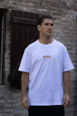 Remera blanca de algodón premium con cuello redondo y mangas cortas. Estampado pequeño en el pecho con tres hongos y la palabra 'Tuya'.