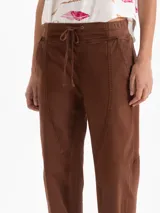 Pantalón tipo babucha de color negro, con cintura elástica y cordón de ajuste, bolsillos laterales y costuras verticales decorativas en el frente.