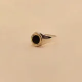 Anillo tipo sello fabricado en plata 925 y oro 9k, con piedra central de onix negro de 7mm de diámetro y detalles grabados en el borde.