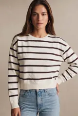 Sweater de algodón con diseño de rayas horizontales en color marrón sobre fondo crudo. Presenta un corte oversize, cuello redondo y puños acanalados, con un pequeño detalle bordado en la parte inferior.