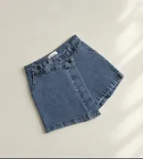 Short pollera de denim azul con diseño cruzado al frente y botones decorativos oscuros.