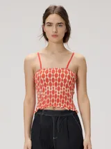 Top de algodón con diseño fruncido tipo smock, estampado geométrico en tonos rojo y beige, corte crop y tirantes finos ajustables.