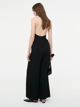 Mono color beige con escote halter, corte holgado, cinturón dorado y pantalones palazzo.