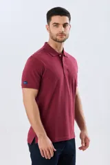 Remera polo lisa de piqué en color bordó, con cuello camisero, cierre frontal con botones y mangas cortas.