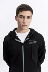 Campera con capucha y cierre frontal, color crema, con bolsillo canguro. Presenta un estampado de texto en el pecho y detalles en el puño.