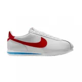 Championes Nike modelo Cortez, de diseño clásico en color blanco con el icónico swoosh lateral en rojo. Presenta detalles en rojo en el talón y una franja azul en la entresuela, con suela dentada característica.
