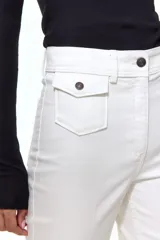 Pantalón de sarga color blanco de corte acampanado y tiro alto, con bolsillos delanteros de parche con solapa y botones oscuros, y pliegues marcados en el centro de las piernas.
