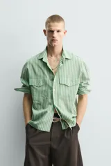 Camisa de corte relajado confeccionada en tejido fluido con mezcla de lyocell. Presenta diseño de rayas verticales, cuello solapa, manga larga con puños abotonados, bolsillos de plastrón con solapa en el pecho y cierre frontal con botones a presión.