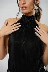 Vestido corto negro plisado con cuello halter y espalda baja. Incluye cinturón de cuero con aros metálicos.