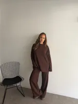 Buzo de punto color marrón chocolate, con cuello redondo y diseño holgado de manga larga con textura de trenzas verticales.