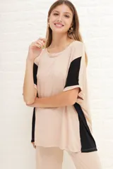 Remerón de manga corta, color beige claro, con bloques de color negro en las mangas. Presenta cuello redondo y un calce holgado.