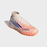 Championes de fútbol Adidas F50 Sparkfusion League, diseñados para mujer. El calzado es de caña media con cuello tejido, exterior en tono beige claro con franjas azules y detalles en naranja coral en la suela.