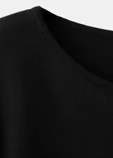 Poncho negro de diseño asimétrico, con cuello redondo y mangas amplias tipo capa.