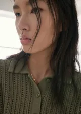 Chaleco de punto verde militar con diseño texturizado, cuello camisero, manga corta y cierre parcial de botones en la parte delantera.