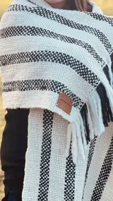 Chal bufandón tejido en telar manual con lana virgen sin teñir y lana negra teñida a mano, con diseño de rayas gruesas. Tiene flecos en los extremos.