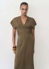 Vestido midi de tejido fluido con diseño evasé, escote en pico y mangas cortas. Presenta un detalle drapeado en los laterales de la cintura y cierre de cremallera invisible en la parte posterior.