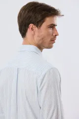Camisa de lino rayada de manga larga, con cuello camisero, cierre frontal de botones y bordado sutil en el pecho.