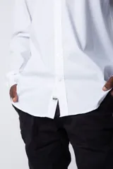 Camisa de manga larga en tela popelín color blanco, con cuello mao y cierre frontal de botones.
