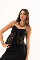 Top de encaje negro con breteles finos, escote con detalle de nudo frontal y diseño con apertura central.