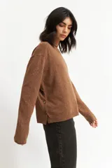 Sweater azul petróleo de tejido de punto, con cuello redondo y botones decorativos en los laterales.