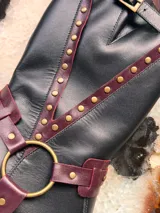 Botas de cuero negro con detalles en color borgoña, hebilla en la parte superior y arnés con aro metálico.